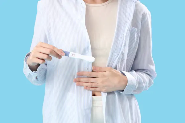 Woman with positive pregnancy test on blue background