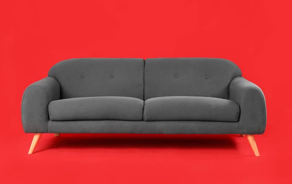 Przytulna Czarna Sofa Czerwonym Tle — Zdjęcie stockowe