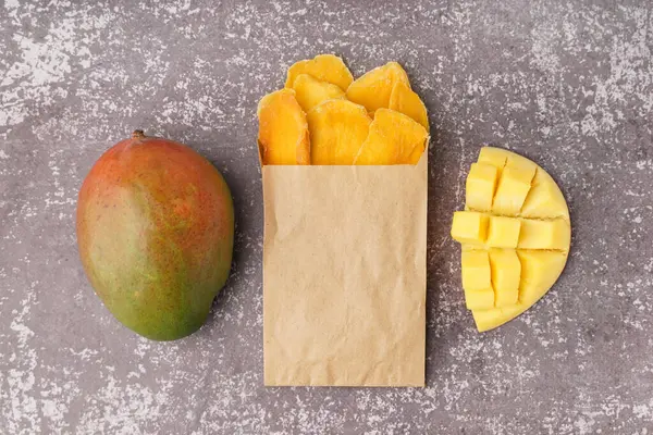 stock image Paper bag with slices of dried mango on dark table