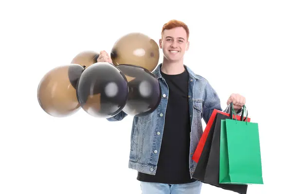 快乐的年轻红头发男人 带着购物袋和气球 背景是白色的 黑色星期五发售 — 图库照片