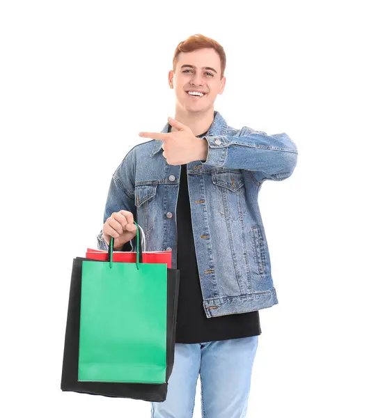 年轻的红头发男人拿着购物袋指着白色背景的东西 黑色星期五发售 — 图库照片