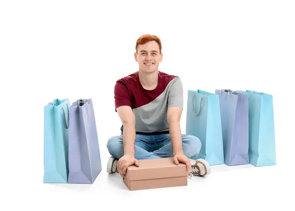 年轻的红头发男子与购物袋和盒子坐在白色背景 黑色星期五发售 — 图库照片