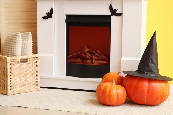 Halloween pumpkins with witch hat near fireplace in living room