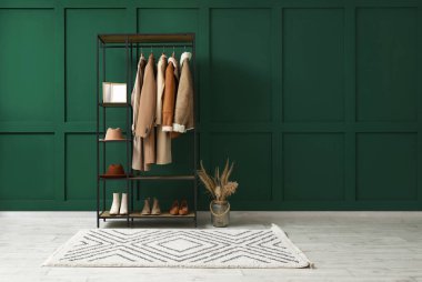 Salondaki yeşil duvarın yanında şapka, çerçeve ve ayakkabı askısı.