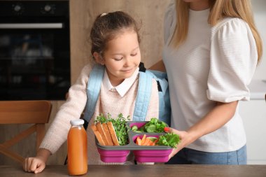 Anne, küçük kızı için mutfakta öğle yemeği hazırlıyor.