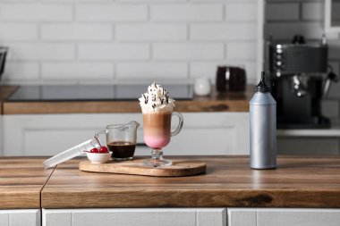 Mutfaktaki ahşap masada kirazlı bir bardak lezzetli kahve ve kase.