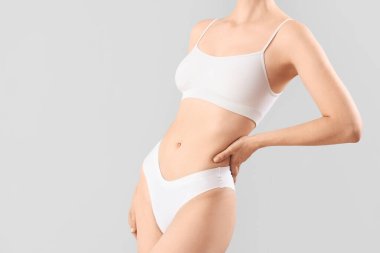 Gri arka planda iç çamaşırlı güzel bir kadın.