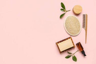 Banyo malzemeleri ve pembe arka planda bitki dalları ile kompozisyon