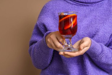 Arka planda bir bardak sıcak şarapla genç bir kadın, yakın plan.