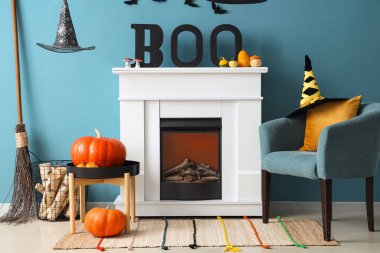 Cadılar Bayramı için dekore edilmiş oturma odasının içinde şömine ve koltuk var.