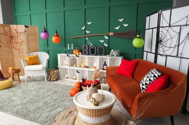 Cadılar Bayramı için dekore edilmiş oturma odasının içinde kırmızı kanepe ve raf ünitesi var.