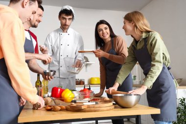 Mutfakta aşçılık kursu sırasında pizza hazırlayan bir grup genci olan İtalyan şef.