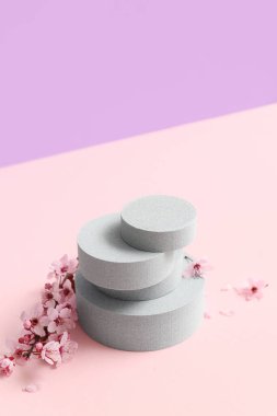 Eflatun arka planda dekoratif podyumlar ve çiçek açan şubeler