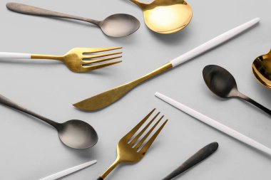 Gri arkaplanda farklı paslanmaz çelik çatal bıçak seti