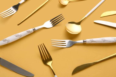 Turuncu arka planda altın ve gümüş çatal bıçak takımı