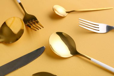 Turuncu arka planda altın ve gümüş çatal bıçak takımı
