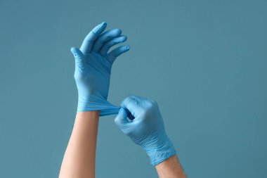 Doktor mavi arka plana lastik eldiven takıyor.