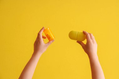 Sarı arka planda ilaç kutusu ve şişe olan bir doktor.