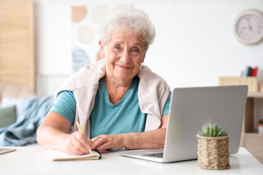 Evde dizüstü bilgisayarda yazan son sınıf öğrencisi kadın.