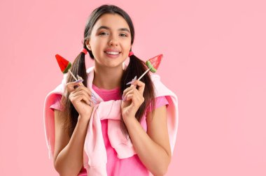 Pembe arka planda karpuz lolipopları olan güzel, mutlu genç bir kadın.