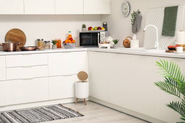 Modern mutfağın içinde şık halı, çöp kutusu ve beyaz tezgahlar var.