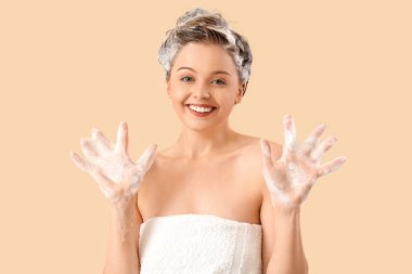 Young woman washing hair on beige background clipart