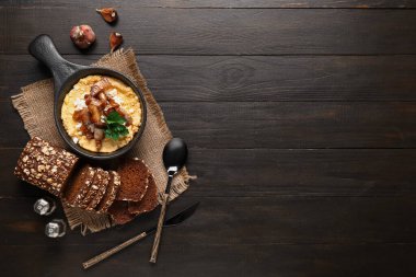 Kızartma tavası ve siyah ahşap arka planda ekmek.