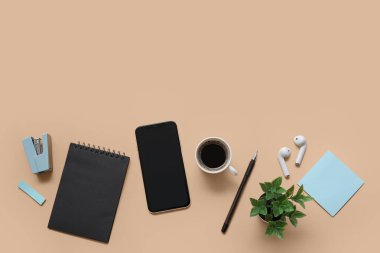 Telefon, kahve ve bej arka planda kırtasiye malzemeleri.