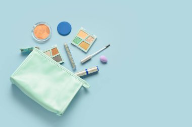 Mavi arka planda farklı dekoratif kozmetik ürünlere sahip çanta