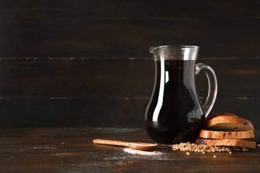 Bir sürahi lezzetli kvass ve ahşap arka planda malzemeler