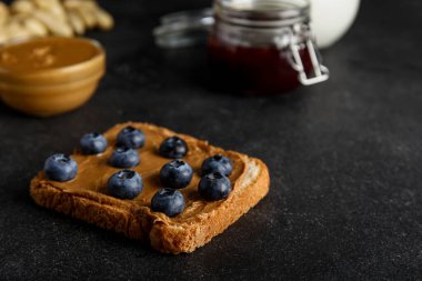 Fıstık ezmeli tost ve siyah arka planda yabanmersini.