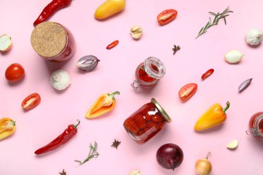 Kavanozlar dolusu domates turşusu ve pembe arka planda farklı baharatlar.