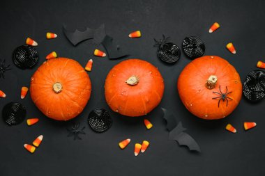 Cadılar Bayramı kompozisyonu balkabakları ve siyah arkaplanda tatlı şekerler