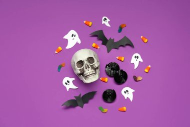 Halloween composition with candies, bats, ghosts and skull on purple background clipart