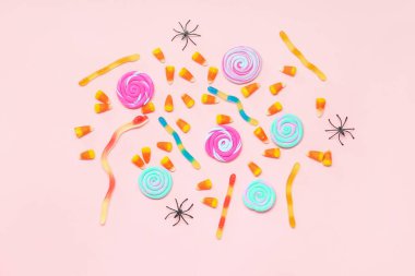 Pembe arka planda farklı tatlı şekerlerle Cadılar Bayramı kompozisyonu