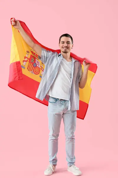 Handsome young man with flag of Spain on pink background