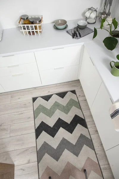 Stylish rug on floor in light kitchen