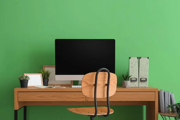 緑の壁の近くの空白のコンピュータ モニターおよび人工植物が付いている現代職場 — ストック写真