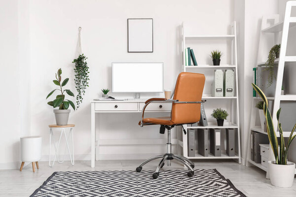 Interior of office with modern workplace, shelving units and artificial plants