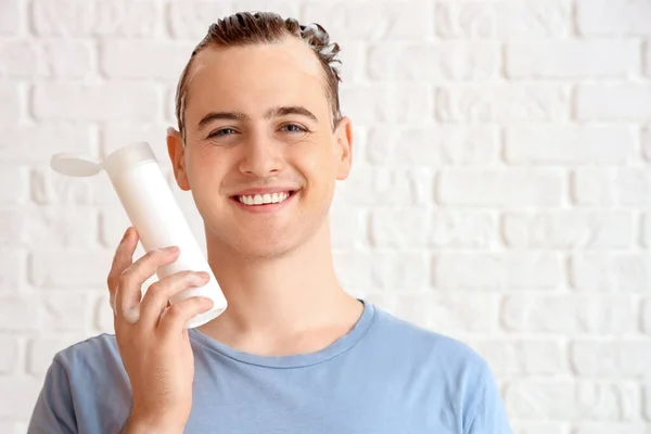 Young Man Bottle Shampoo White Brick Background — Stock Photo, Image
