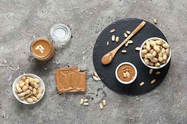 Toast with peanut butter and nuts on grey background