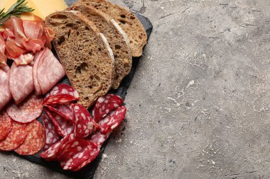 Lezzetli mezeler ve gri arka planda ekmekle kaplanmış bir tabak, yakın plan.