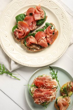 Beyaz ahşap arka planda jambonlu lezzetli bruschetalar.