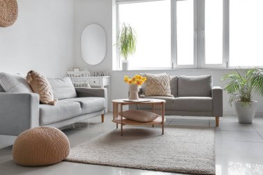 Kahve masasının üzerinde rahat kanepeler ve vazo olan modern oturma odasının içinde.
