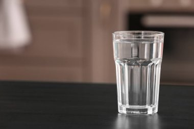 Mutfaktaki siyah masada bir bardak su.