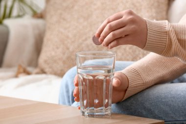 Ateşli tableti bir bardak suya koyan kadın.