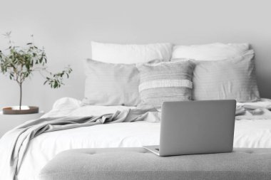 Yatağın başındaki bankta modern laptop, yakın plan.