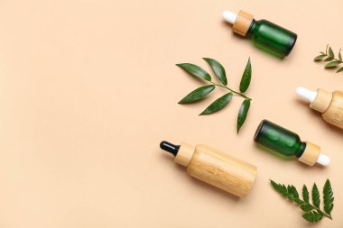 Bej arka planda bitki dalları olan kozmetik yağı şişeleri