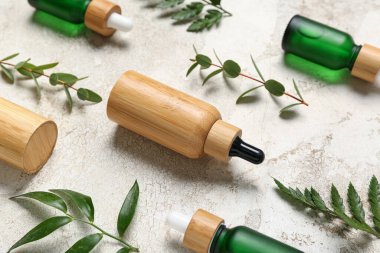 Arkaplanda bitki dalları olan kozmetik yağı şişeleri.