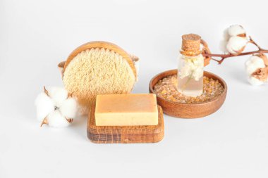 Sabun çubuğu, masaj fırçası, deniz tuzu, temel yağ ve pamuk çiçekleri beyaz arka planda